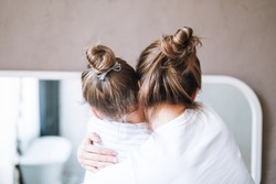 Young mother woman with long hair with little tween girl daughter in pajamas having fun in the morning at home, family spending time together in bathroom