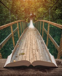Way by the suspension bridge in a misty forest on the pages of an open magical book. Majestic landscape. Nature and education concept.