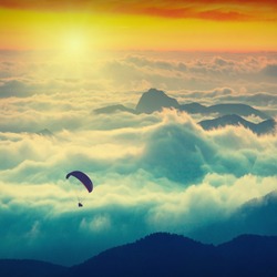 Paraglide silhouette over mountain peaks. Sunrise in a high mountains foggy valley of Crimea, Ukraine