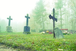 Old crosses on the graves in a cemetery in the autumn morning fog - village Ergeme in Valka municipality, Latvia 
