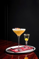 Pornstar martini cocktail with passion fruit and vodka, served with sparkling wine in a separate glass on a silver tray