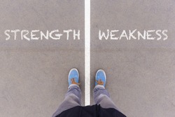 Strength and weakness text on asphalt ground, feet and shoes on floor, personal perspective footsie concept