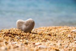 Stone heart on the pebble beach in the background the sea close up/ A stone in the shape of a heart close up/ Stone heart
