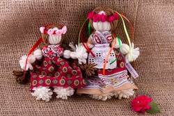 Two rag dolls in tunics and wreaths with ribbons on a background of burlap, handmade, the doll is made without using needles