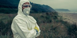 Man in bacteriological protective suit watching to the sea