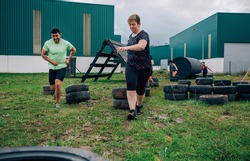 Group of participants in an obstacle course dragging wheels seen from behind