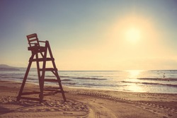 Baywatch chair in a beautiful beach empty at summer sunset. Soft and warm tones edition.