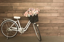 flower in basket of vintage bicycle on vintage wooden house wall