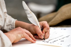 hands while writing a letter with a plume