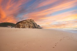 Aerial view of waves on a beautiful sandy ocean beach and cliff at the sunset. Panorama atlantic coastline.