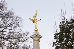 Gold winged Victory statue in World War I Memorial in Washington DC with trees. Soft focus