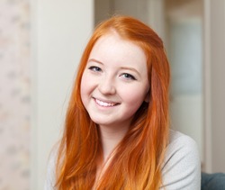 Portrait of smiling red-haired tenager girl in home