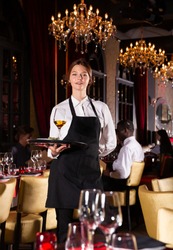 Portrait of smiling waitress with tray at luxury restaurant