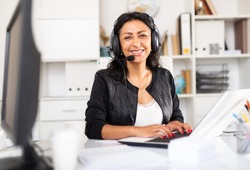 Portrait of smiling Peruvian woman helpline operator with headphones during work in call center