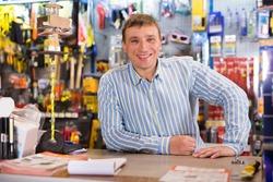 Fine seller man in hardware store is trading tools