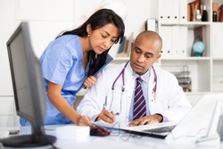 Doctor and nurse check patient data in hospital computer database