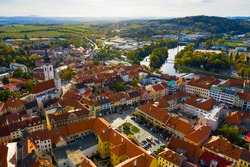 Aerial view of Old Town of Czech city of Pisek on Otava river overlooking white belfry of Church of Nativity of Blessed Virgin Mary on fall day