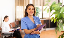 Portrait of confident smiling woman medical worker standing in clinic office