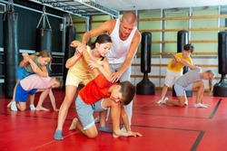 Young children working in pair mastering new self-defense moves at gym