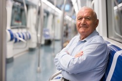 Elderly man sitting on bench inside subway car and waiting for his stop.