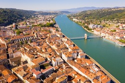 General view of Vienne city on banks of Rhone river surrounded by high hills in sunny summer day, Isere, France