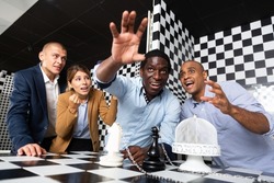 Multiracial people trying to find solution of conundrum in chess escape room