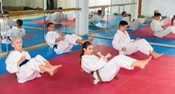 Group of sporty people in white kimonos doing warm up before martial arts training in gym..