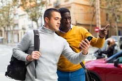 European man with smartphone having conversation with African-american man about directions.