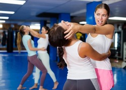 Determined young woman attacking eyes of female partner as self-defense tactic during workout in practice hall..