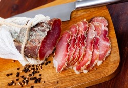 Sliced Polish cured sirloin pork polendvitsa on wooden cuting board. Traditional meat delicacies..