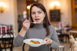 Woman enjoying slice of traditional apple strudel with vanilla sauce in coffee house while traveling in Vienna..