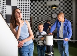 Thoughtful young woman visiting black and white quest room with her husband and two sons, trying to solve conundrums