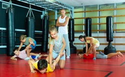 Kids training armlock move during group self-protection training.