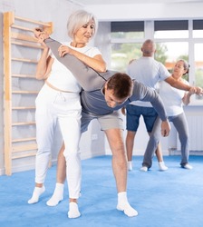 In gym female pensioner work out skill at sparring bout and perform basic elements of krav maga self-defense system. Preparation of athletes before competitions