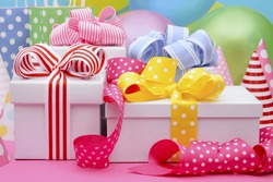 Bright colorful party table with balloons, streamers, party favor gift bags and gifts with bright color ribbons and bows. 