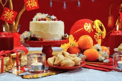 Chinese New Year party table in red and gold theme with food and traditional decorations.