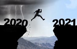 Man jumps over abyss with thunderstorm in background and inscription 2020 and 2021.