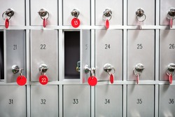 Rows of metal lockers with numbered keys with red tags for storing valuables and personal possessions in a full frame view