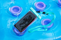 Mobile phone encased in a clear plastic waterproof case for protection against water and moisture in summer while enjoying water sports outdoors