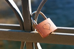 Love lock engraved with a heart to signify commitment and lifelong love locked on a wrought iron railing or balustrade, a trendy fad by tourists considered an act of vandalism by town authorities