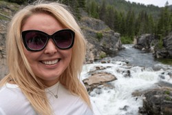 Woman poses by Dagger Falls waterfall in Idaho in the Salmon-Challis National Forest