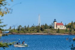 Copper Harbor Lighthouse on Lake Superior, with defocused fishermen in a boat