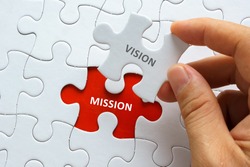 Hand holding piece of jigsaw puzzle with word VISION MISSION.