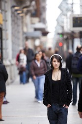 Young girl with headphones standing on sidewalk