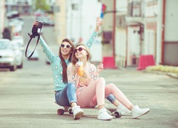Hipster fashion girlfriends taking a self photo in urban city context seat on skate keep moment with modern digital camera