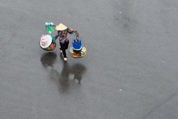 Unidentified street vendor on street in a raining day in Hanoi, Vietnam