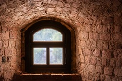 Brown window with an arch in a recess in the wall made of old red brick. From the window of the world series.