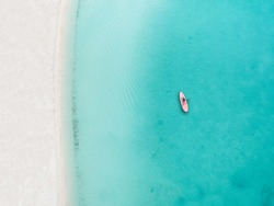 Drone photo of beach in Grace Bay, Providenciales, Turks and Caicos. The caribbean blue sea and underwater rocks can be seen, as well as some jet skies