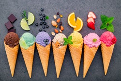 ice cream flavor in cones blueberry ,lime ,pistachio ,almond ,orange ,chocolate ,vanilla and coffee set up on dark stone background . Summer and Sweet menu concept.