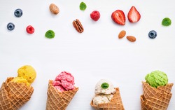 Colorful  ice cream with cones and various fruits raspberry ,blueberry ,strawberry ,almonds and peppermint leaves setup on white background . Summer and Sweet menu concept flat lay and copy space .